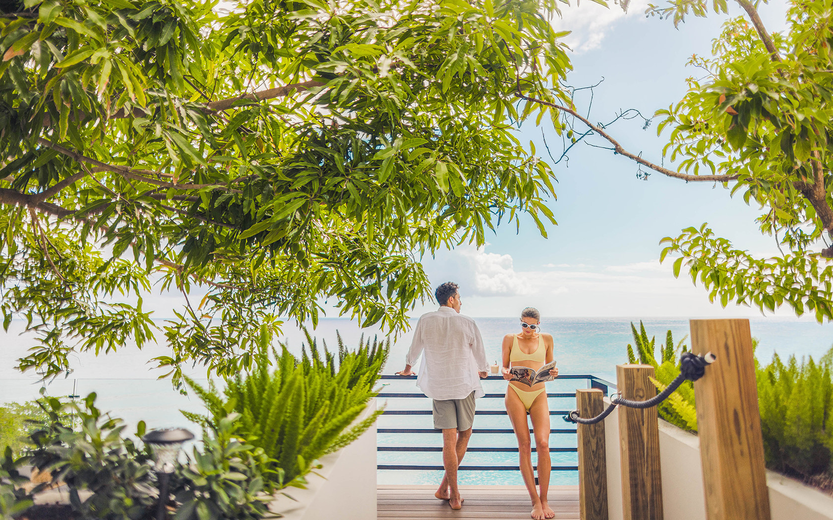 man looking out at ocean and woman reading